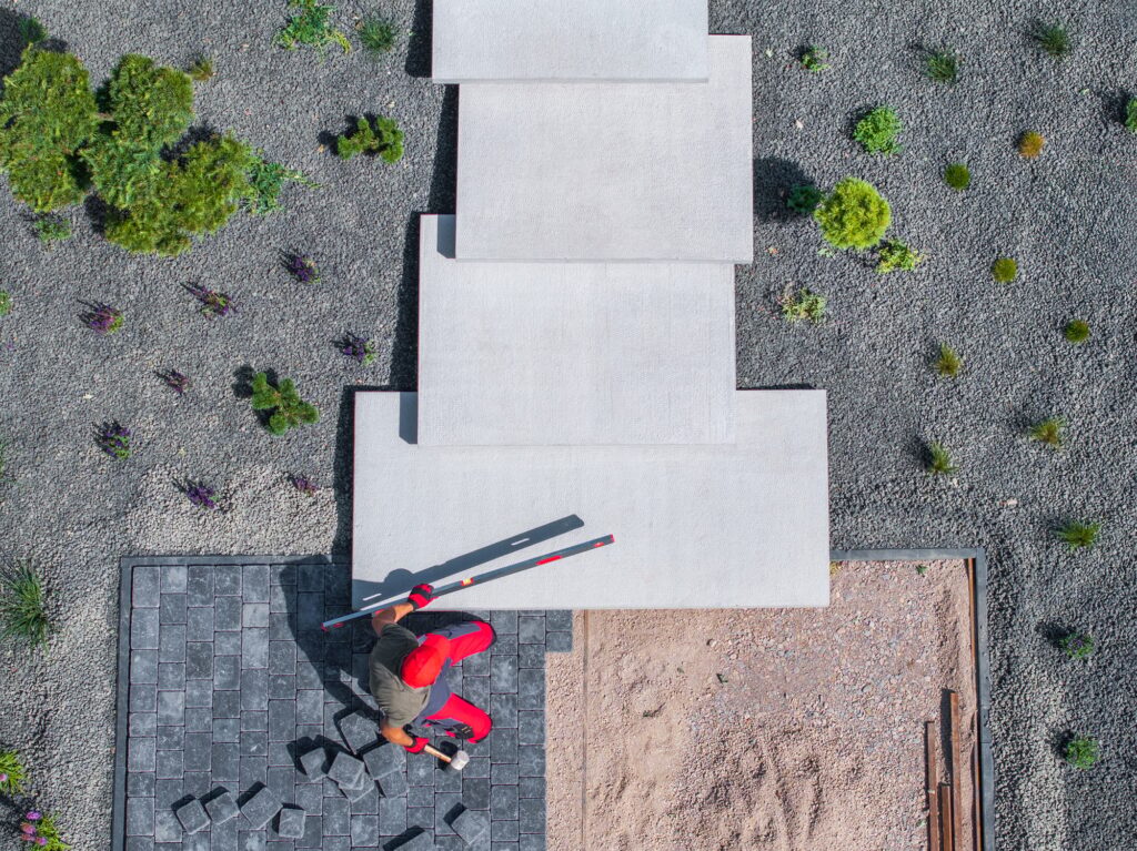 Construction Worker Installing Concrete Steps in a Landscaped Garden During Daytime