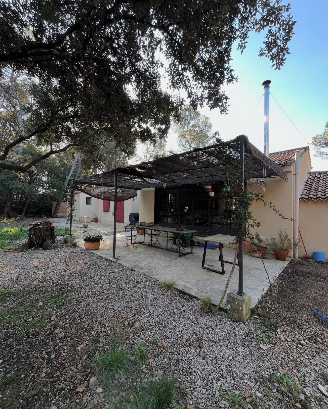 Espace extérieur paysager avec terrasse pavée, zone de gazon et plantations devant maison contemporaine.